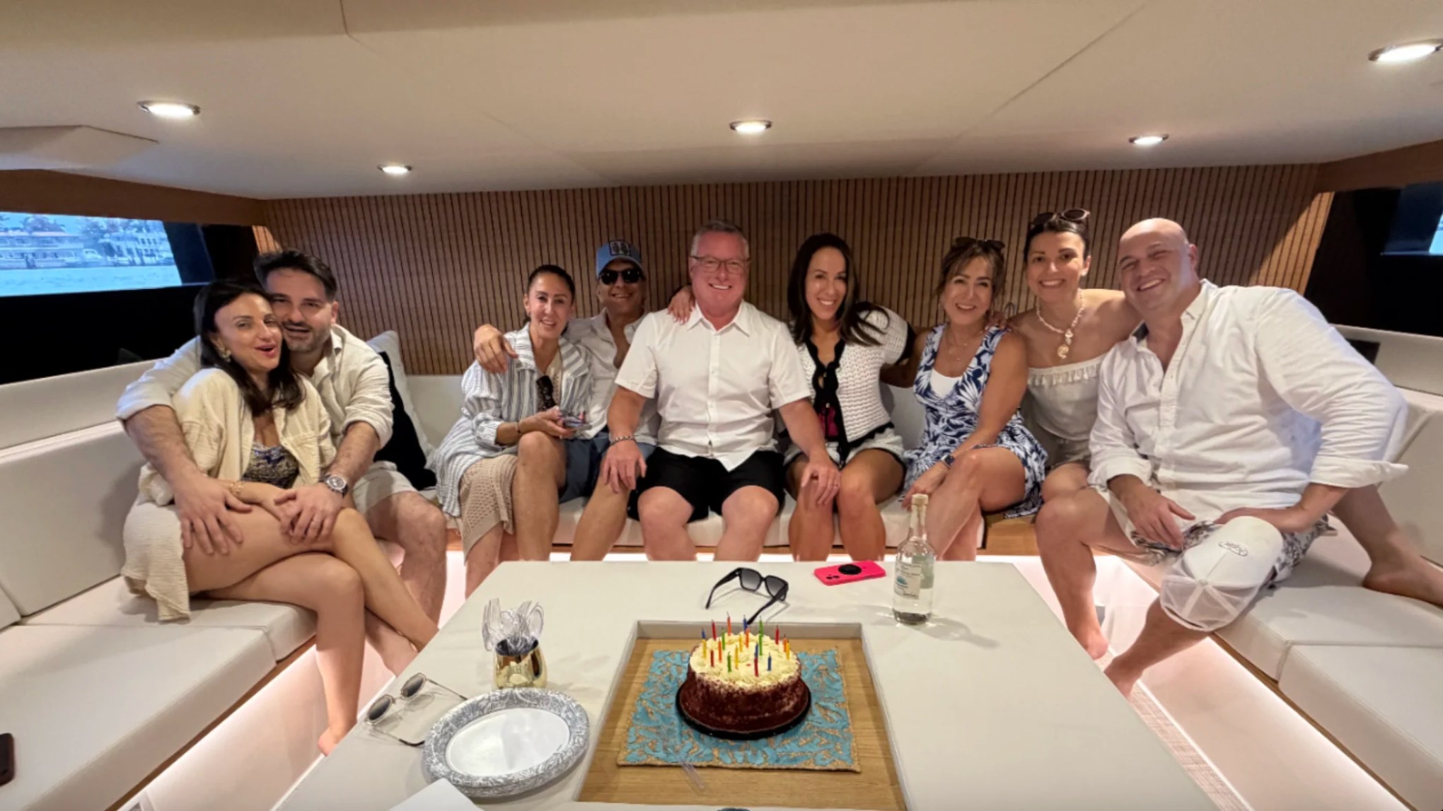 Guests celebrating a special occasion inside the spacious salon aboard a 50' DeAntonio Yacht Charter in Palm Beach featuring contemporary lounge seating and elegant interior design.