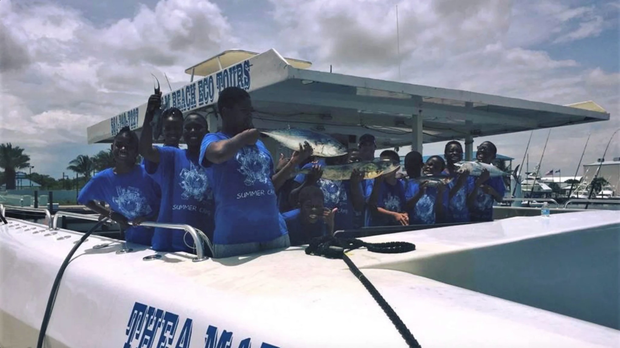 Youth group celebrating a successful fishing trip aboard a 49' PowerCat Boat Rental in Riviera Beach Florida.