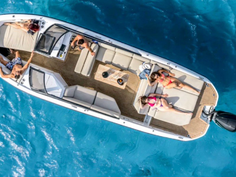 Aerial view of guests relaxing on the spacious open deck of a 29' RAND Boat Rental in clear tropical water.