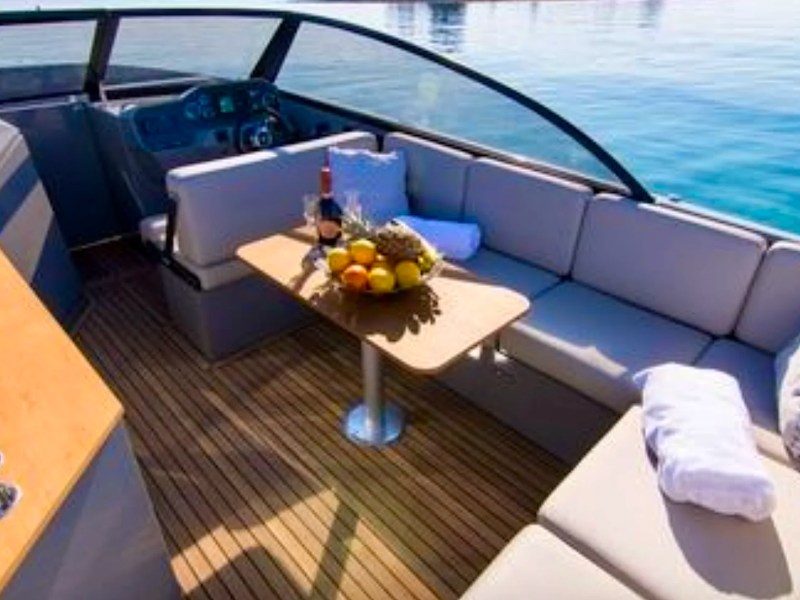 Spacious cockpit lounge with dining table and wet bar aboard a 29' RAND Boat Rental in Riviera Beach, Florida.