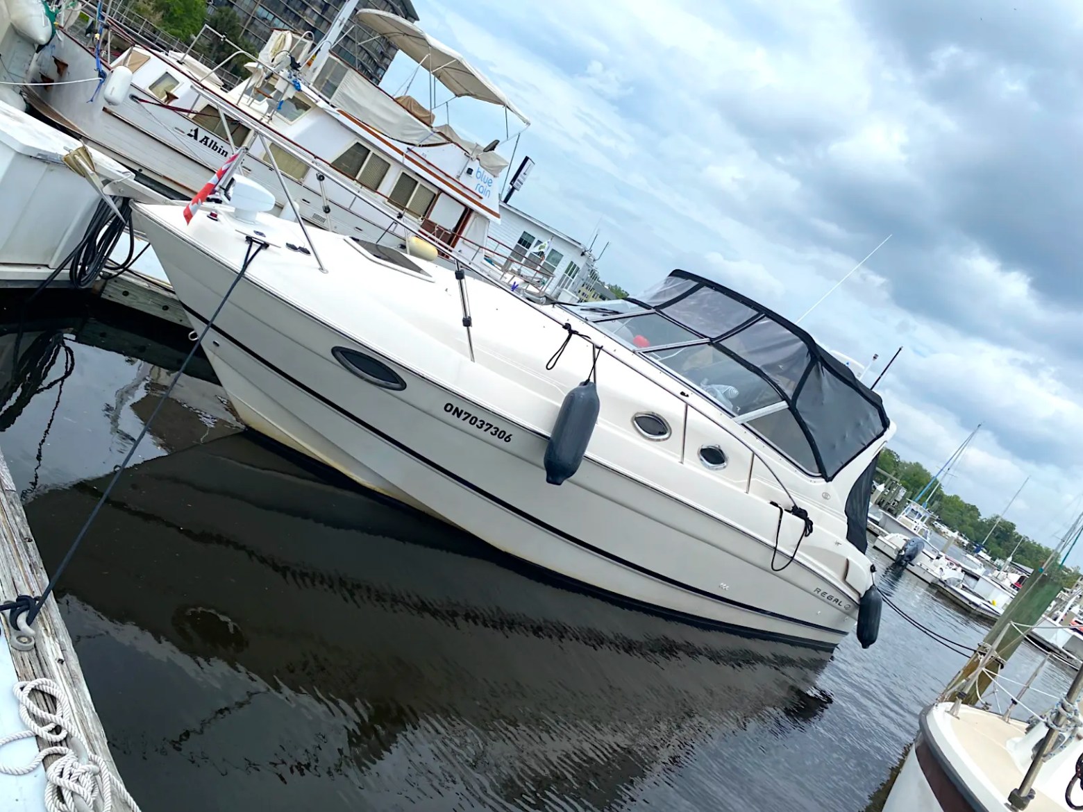 33' Regal Boat Rental docked at a Jacksonville marina with enclosed cockpit and sleek white hull.