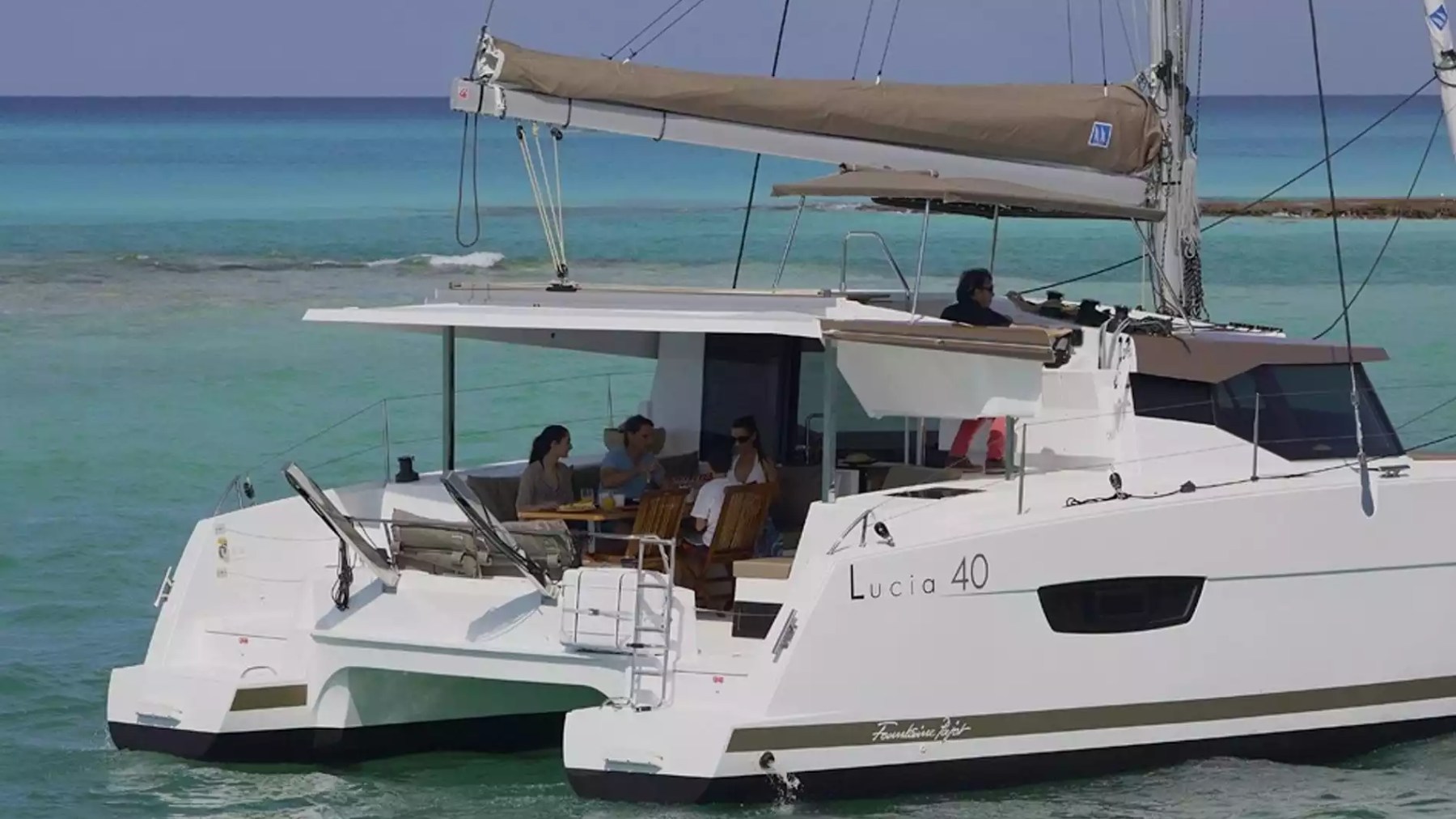 40' Fountaine Pajot Boat Rental with shaded aft cockpit dining and guests relaxing on tropical waters.