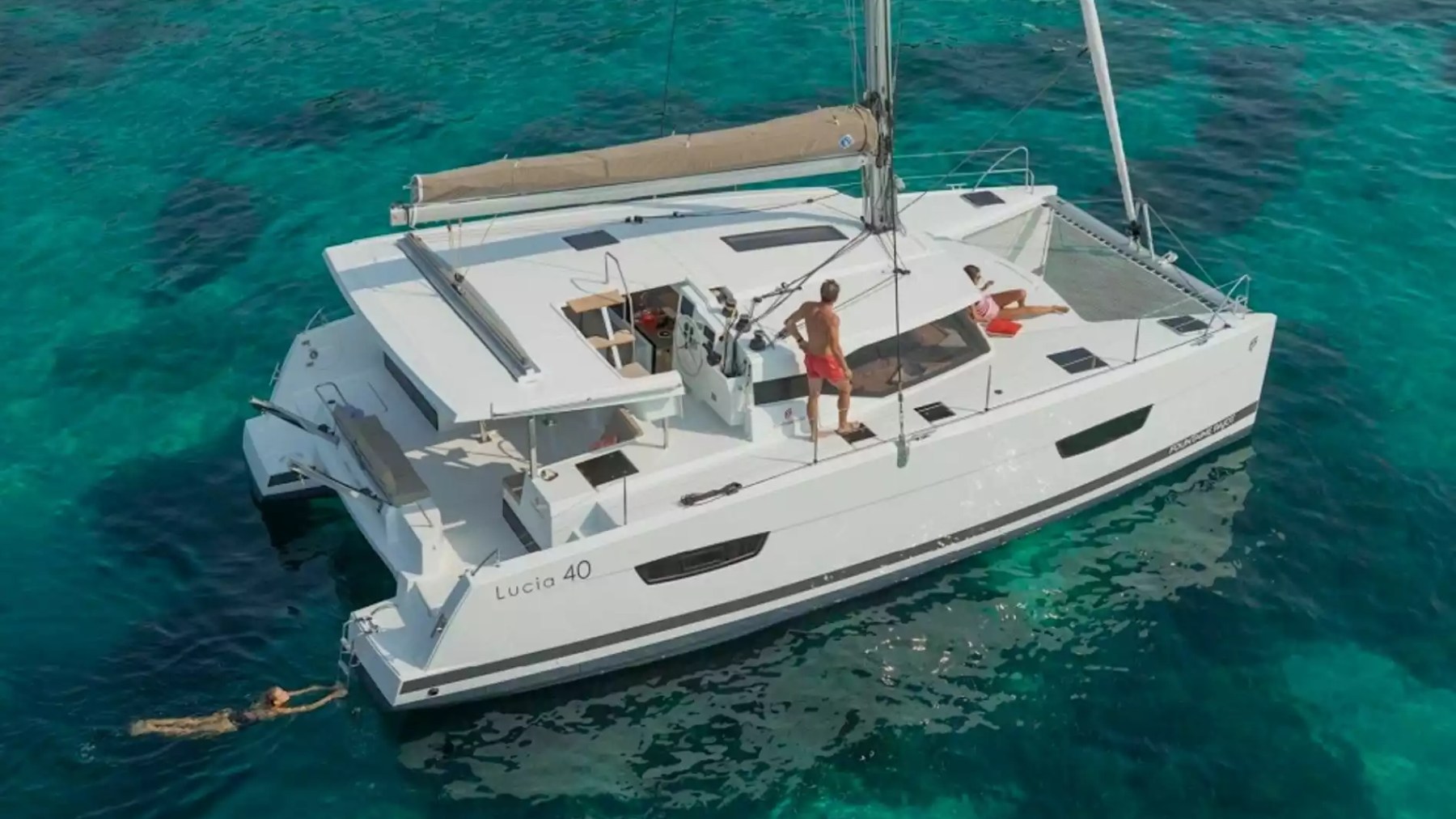 40' Fountaine Pajot Boat Rental anchored in turquoise water with guests swimming and relaxing on the spacious deck.