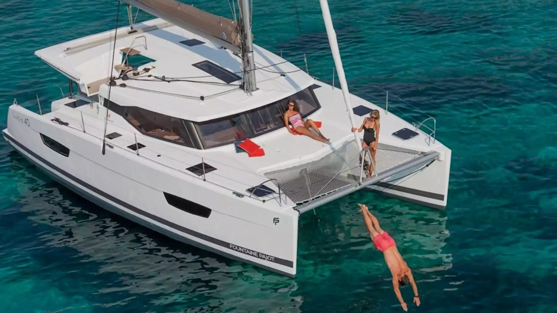 40' Fountaine Pajot Boat Rental with bow trampoline, sunbathing area and guests swimming in tropical waters.
