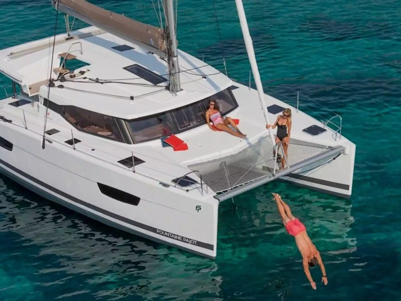 40' Fountaine Pajot Boat Rental with bow trampoline, sunbathing area and guests swimming in tropical waters.