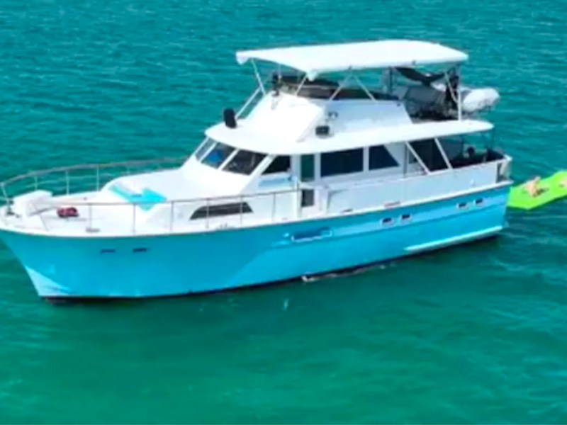 Aerial view of a 53' Hatteras Yacht Charter anchored in turquoise Key West waters with guests relaxing on a floating water mat.