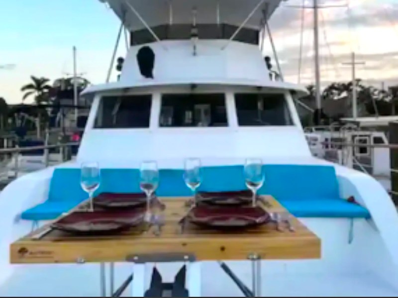 Outdoor dining table with turquoise lounge seating aboard a 53' Hatteras Yacht Charter in Key West, Florida.