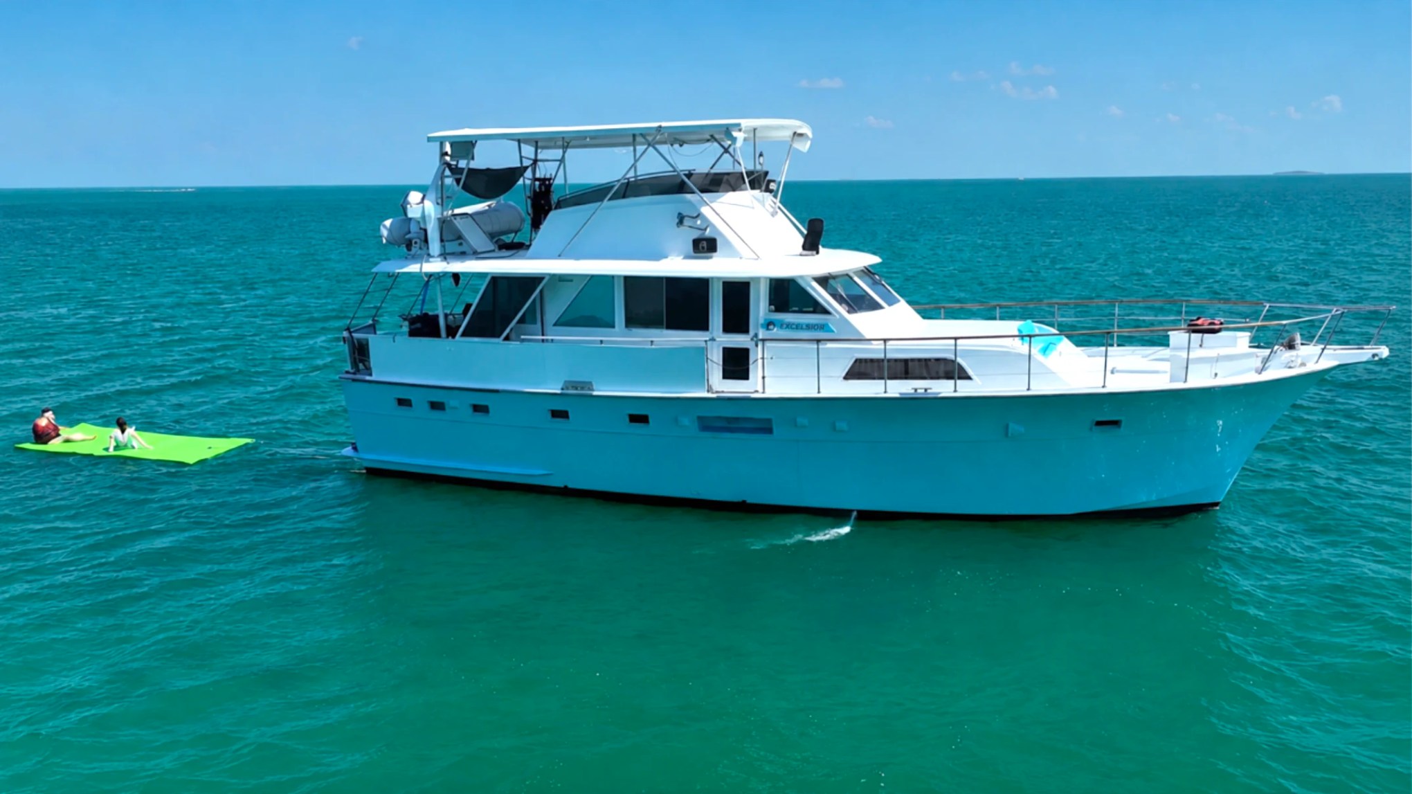 53' Hatteras Yacht Charter anchored in turquoise Key West waters with guests relaxing on a floating water mat.