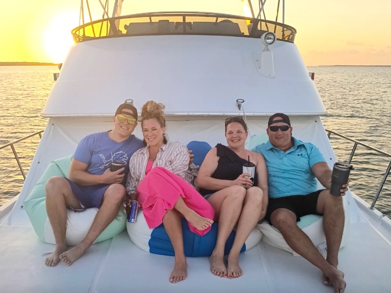 Guests relaxing on the bow of a 55' Californian Yacht Charter at sunset in Key Largo, Florida.