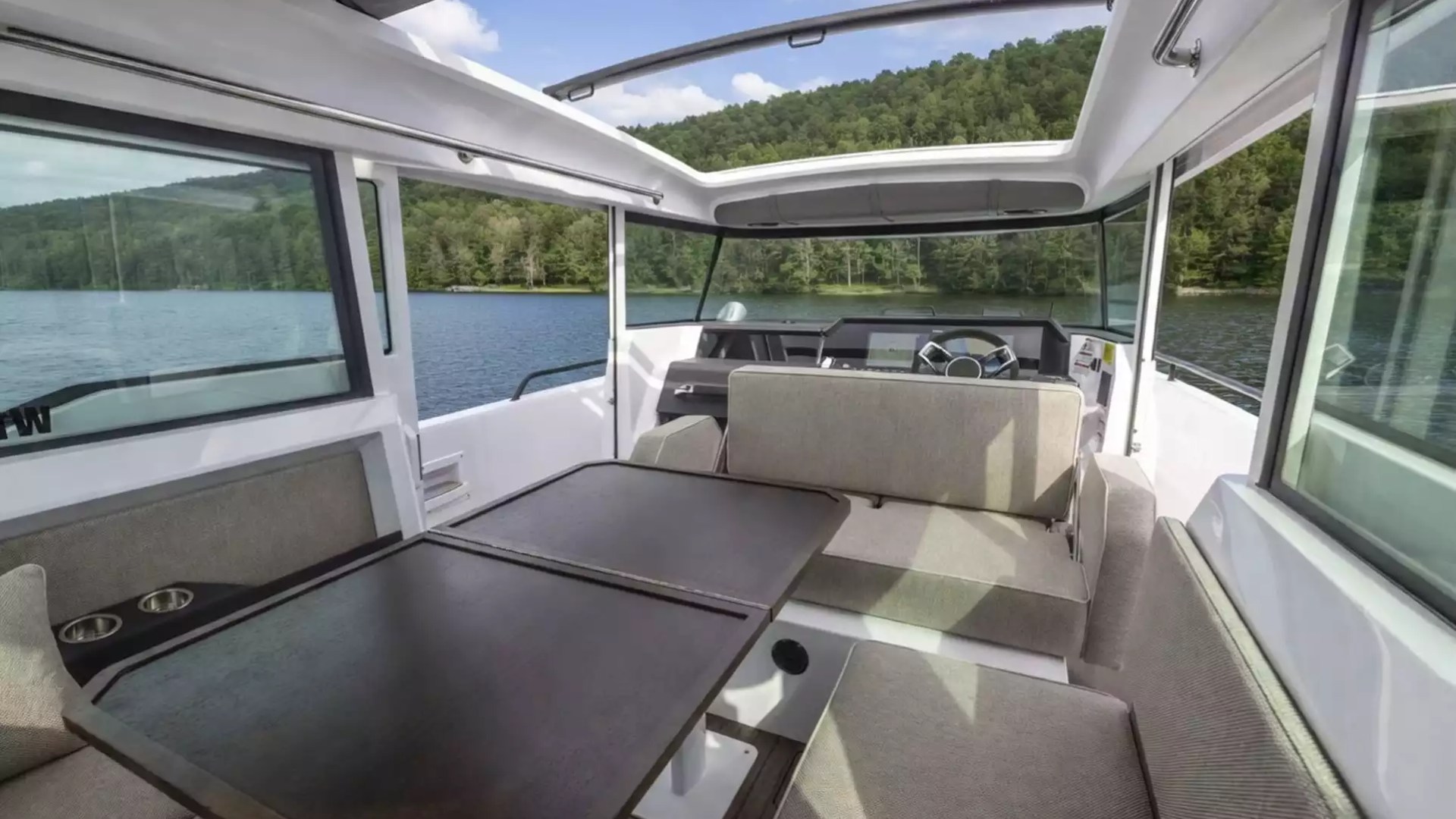 Axopar Boat Rental cabin with panoramic windows, dining table, lounge seating and helm overlooking the water.