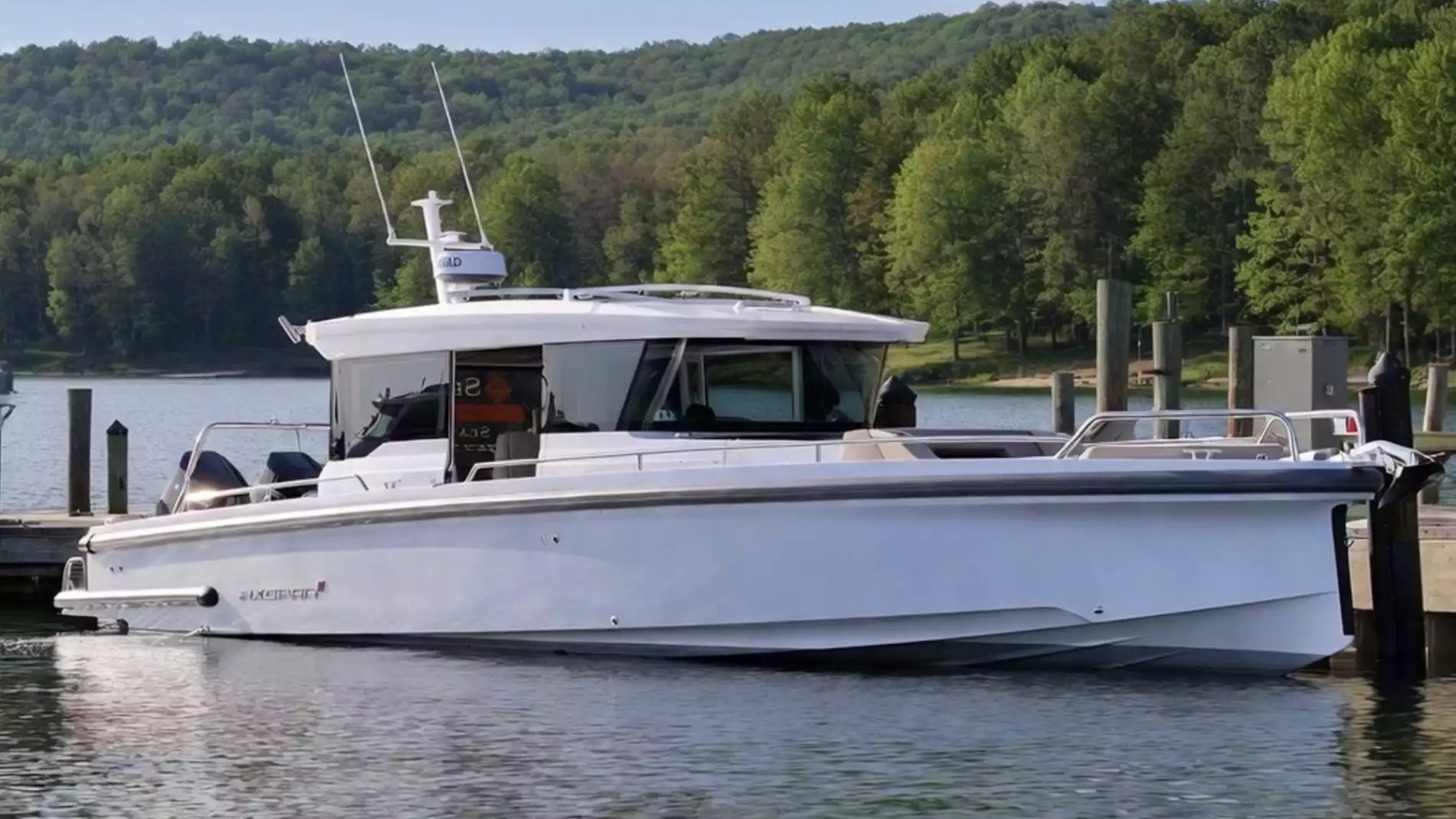 Axopar Boat Rental docked on calm water with enclosed pilothouse, open bow and panoramic waterfront views.