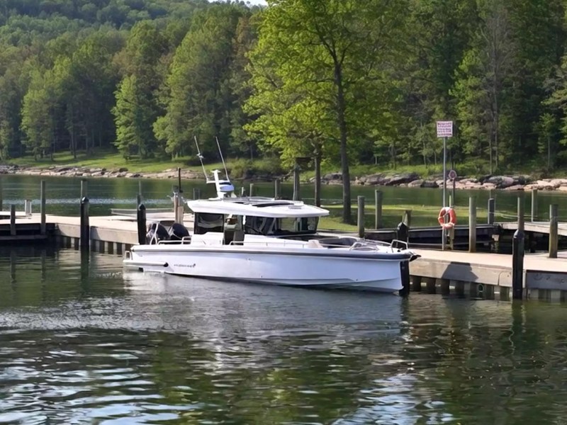Axopar Boat Rental docked at a lakeside marina with wooded hills and calm water.