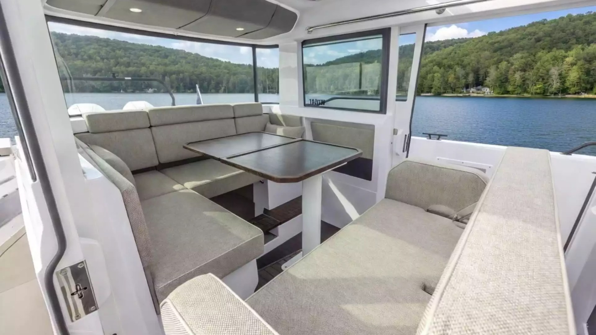 Axopar Boat Rental cabin with wraparound lounge seating, dining table and panoramic waterfront views.