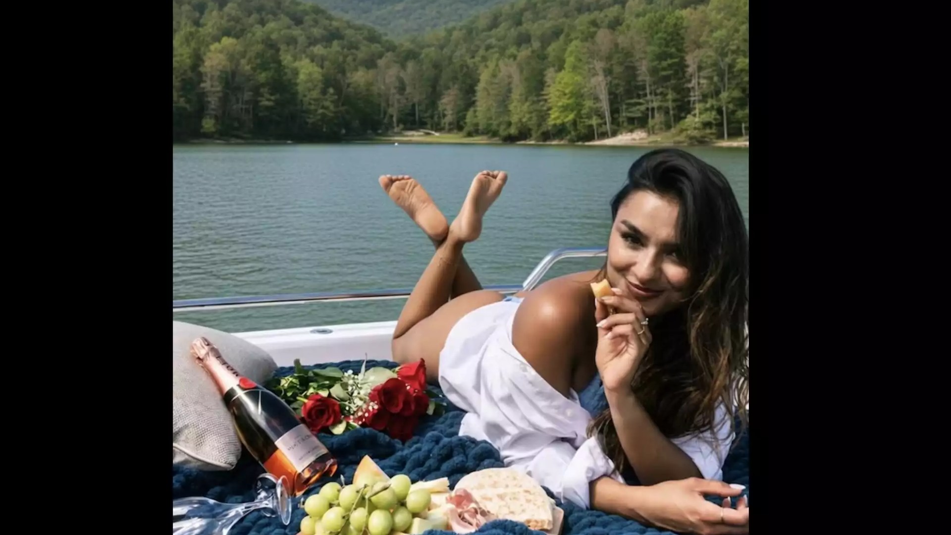 Woman relaxing on an Axopar boat with roses, refreshments and scenic waterfront views during a private outing.