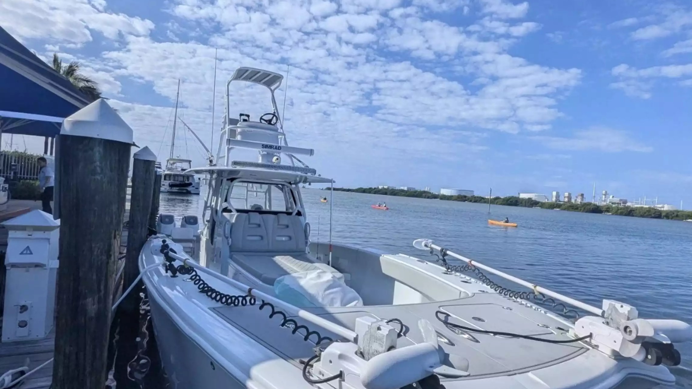 Center console fishing boat docked with elevated tower, open bow deck and trolling motors ready for a day on the water.