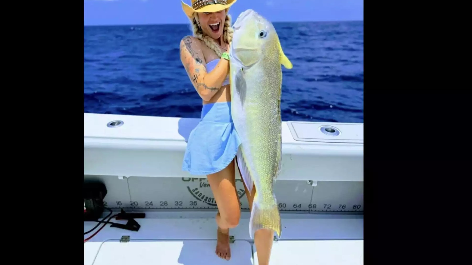 Woman holding a large trophy fish during an offshore fishing trip aboard a center console boat.