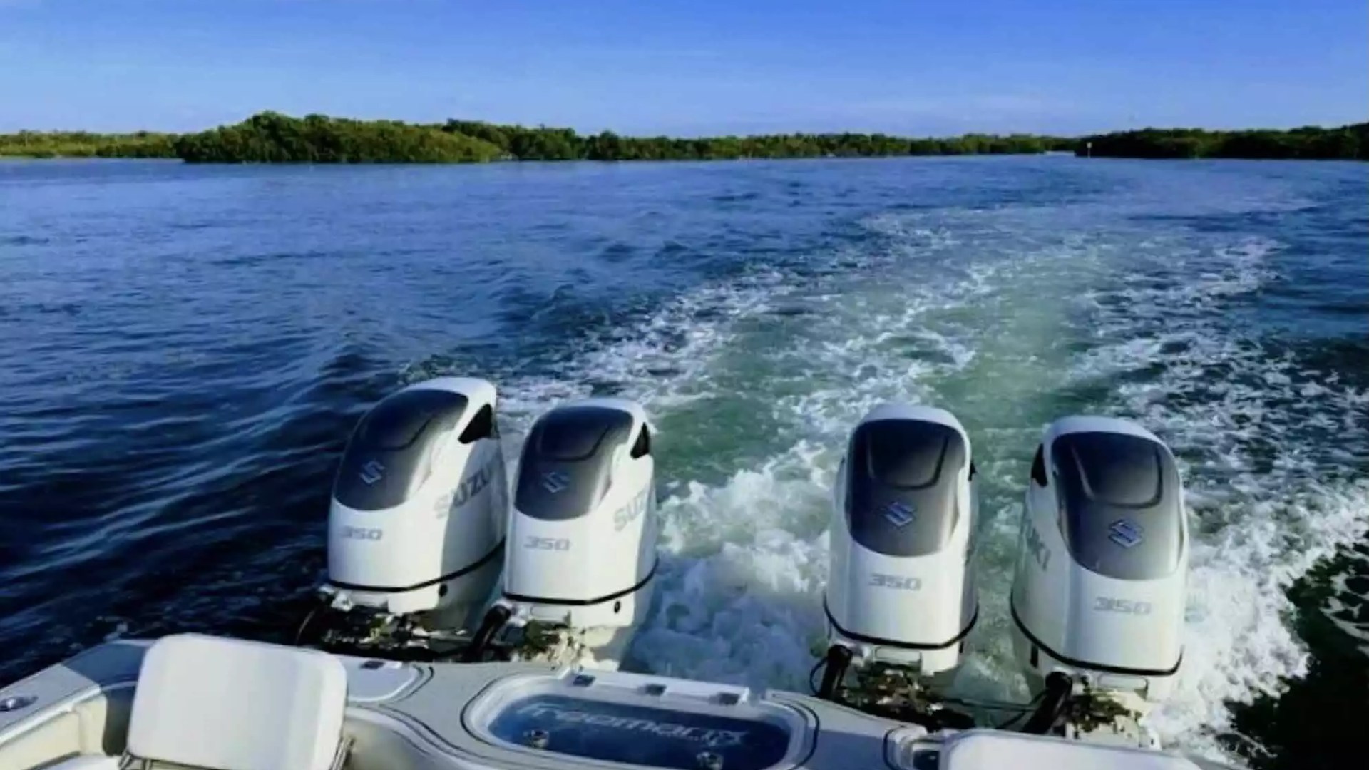 Center console fishing boat underway with four Suzuki 350 outboard engines and a powerful wake across open water.