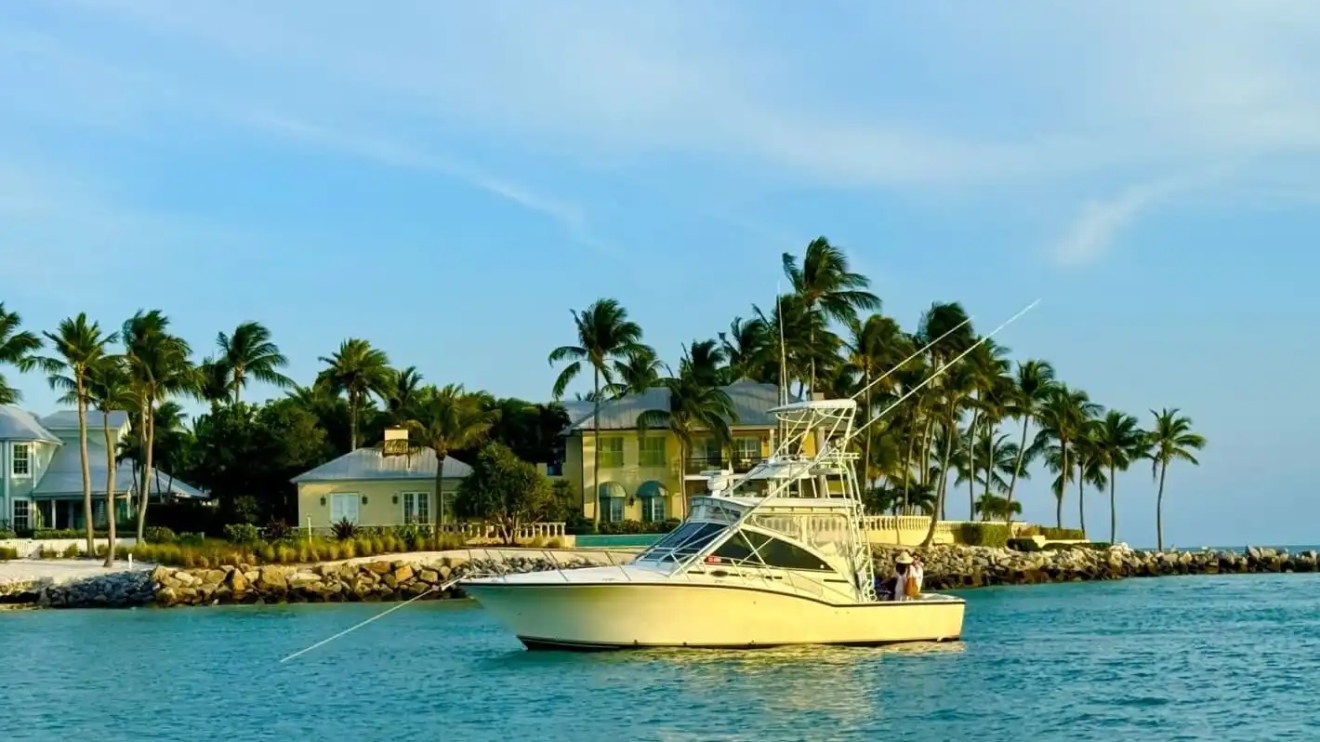 Key West Sportfishing Boat Rental anchored in turquoise water near a palm-lined Florida Keys waterfront.