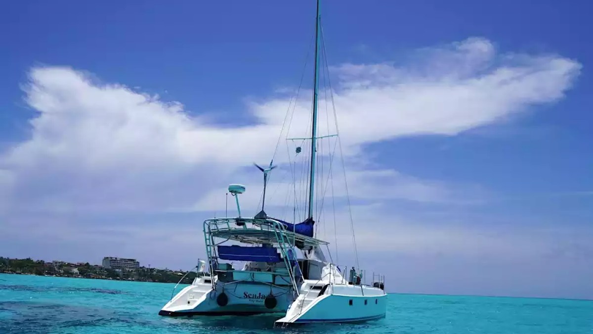 Sailing catamaran anchored in clear turquoise tropical waters under a bright blue sky.