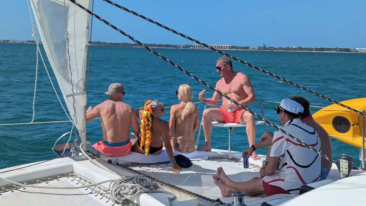 Sailing catamaran with guests relaxing on the spacious bow trampoline during a sunny day on the water.