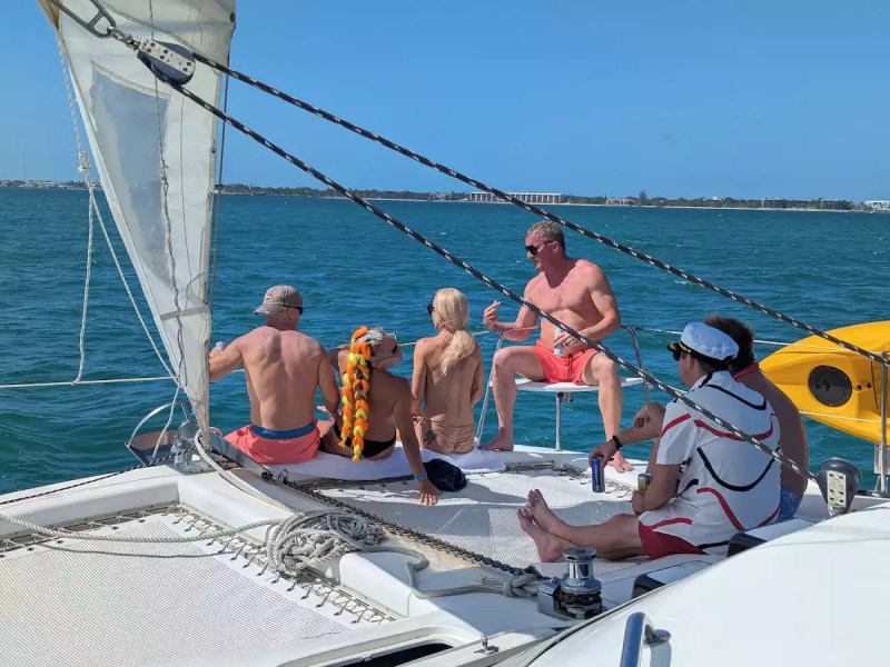 Sailing catamaran with guests relaxing on the spacious bow trampoline during a sunny day on the water.