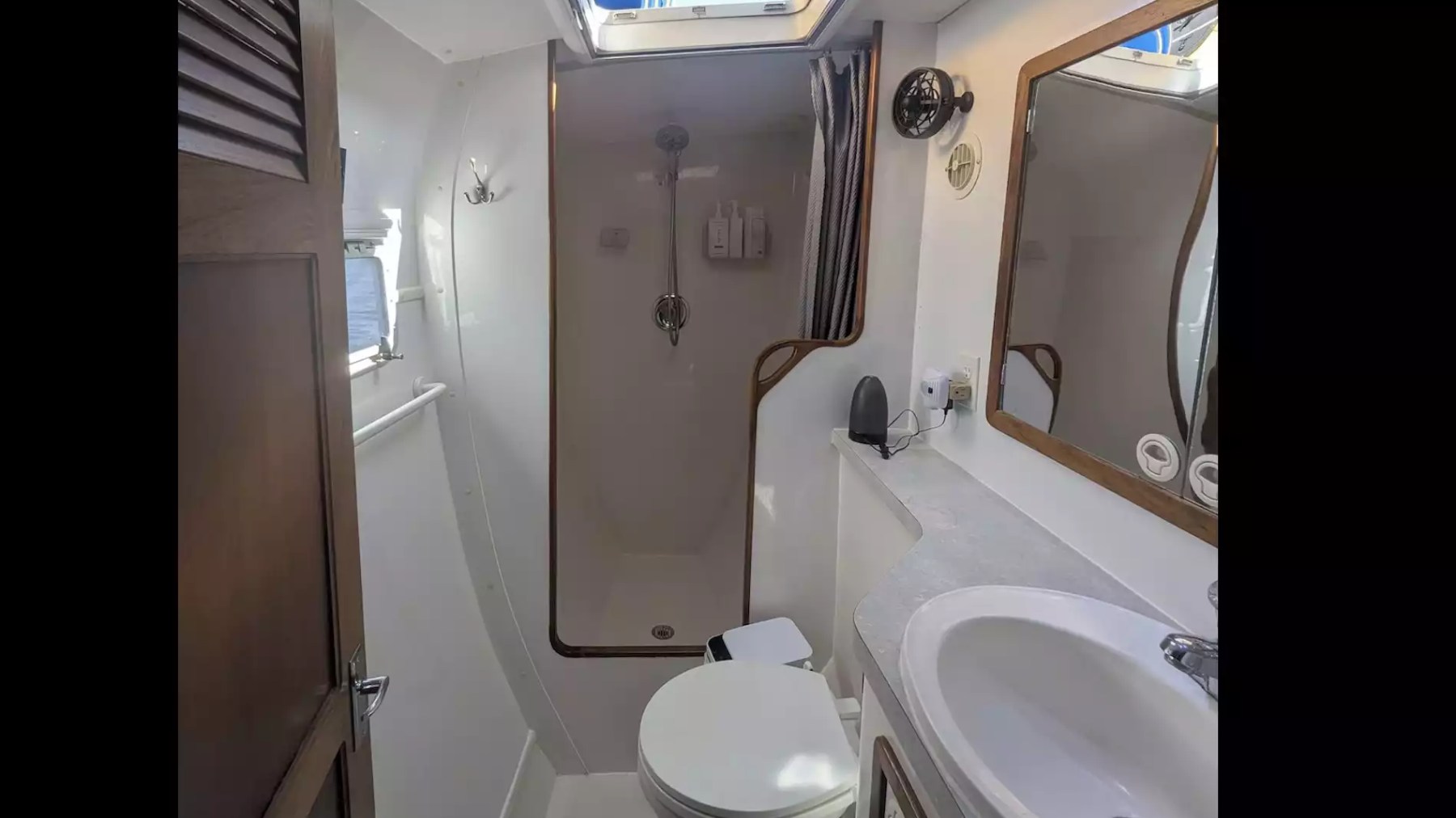 Sailing catamaran private bathroom with walk-in shower, vanity, sink and overhead skylight.