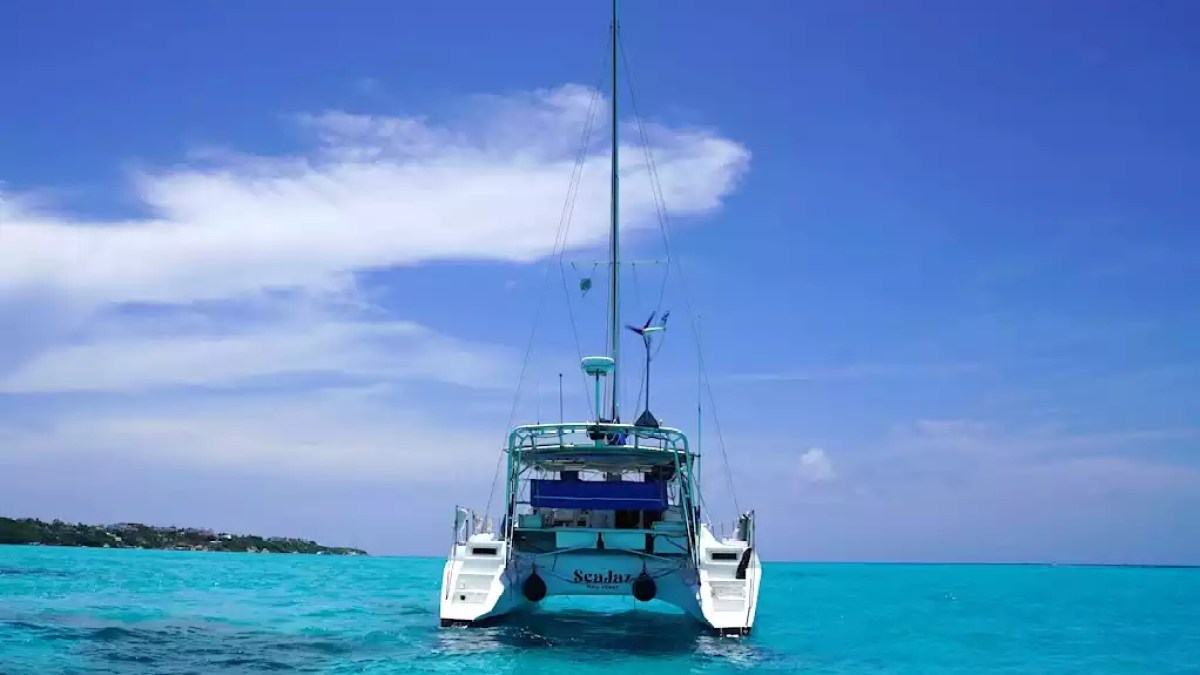 Sailing catamaran anchored in vivid turquoise tropical water beneath a clear blue sky.