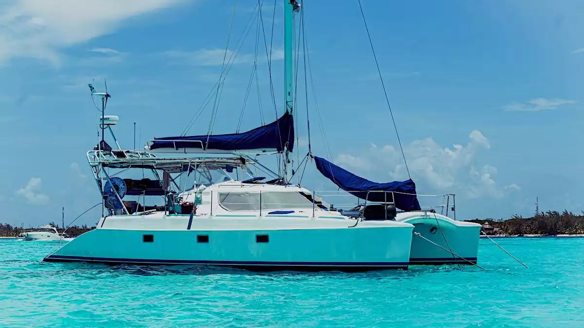 Sailing catamaran anchored in clear turquoise tropical water with spacious deck and shaded cockpit.