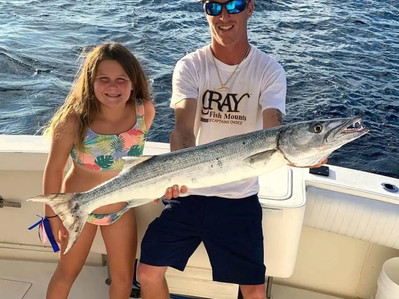 Sportfishing Boat Rental guests displaying a large barracuda after an offshore fishing trip.