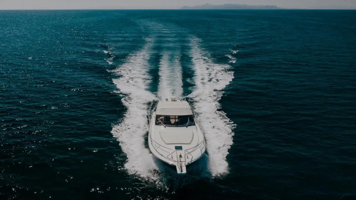 44' Uniesse Boat Rental underway with a dramatic aerial bow view and wide wake in Naples, Florida.