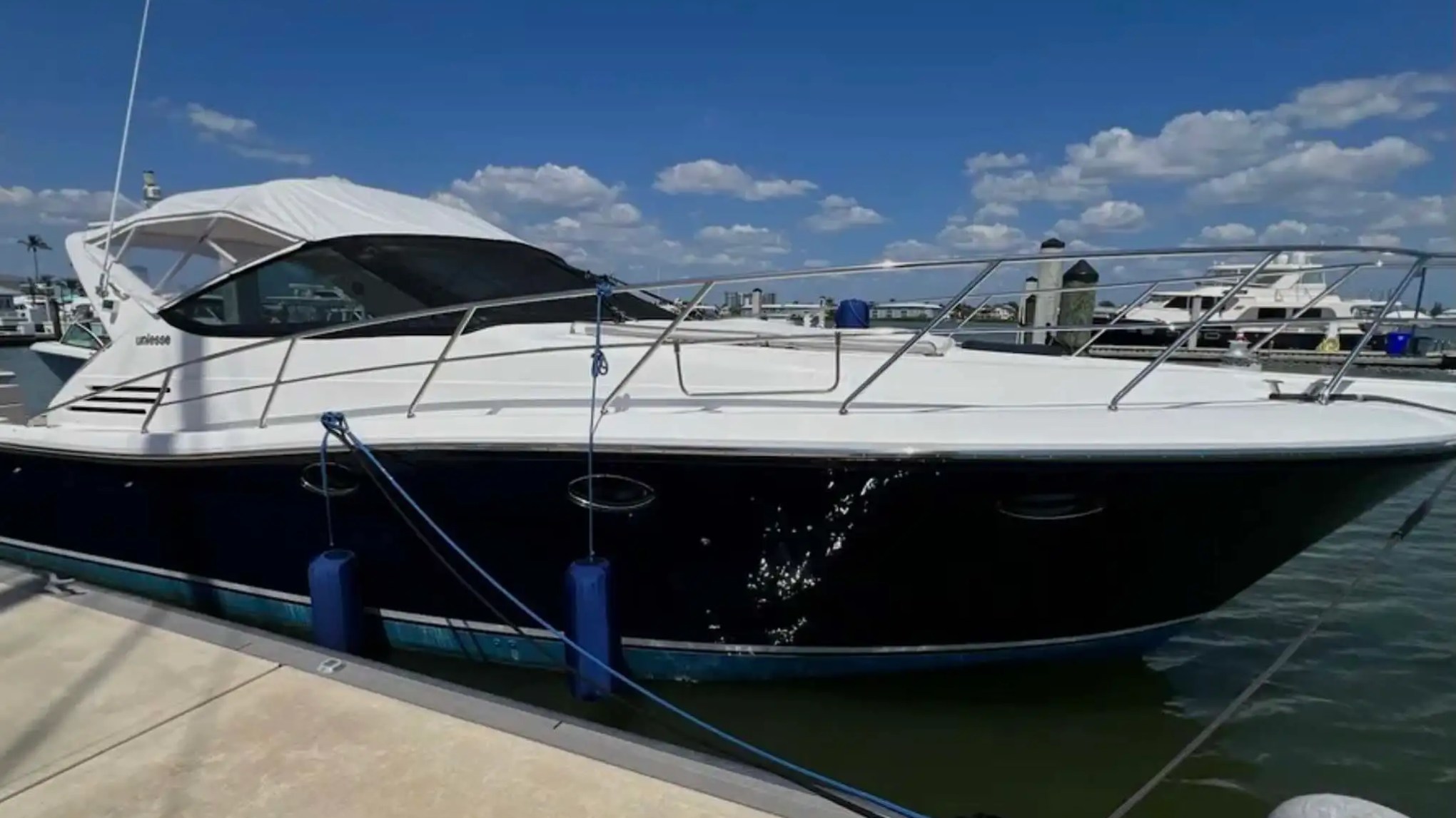44' Uniesse Boat Rental docked at a Naples marina with sleek dark hull and spacious bow deck.