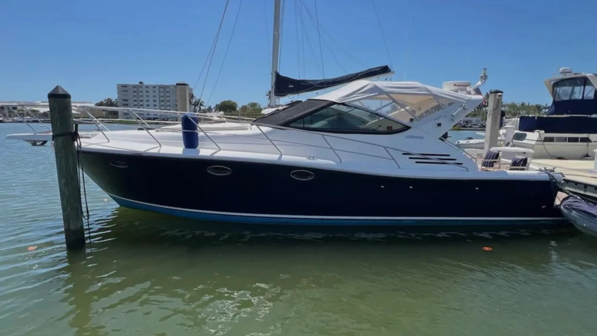 44' Uniesse Boat Rental with sleek profile and navy hull at a marina in Naples, Florida.