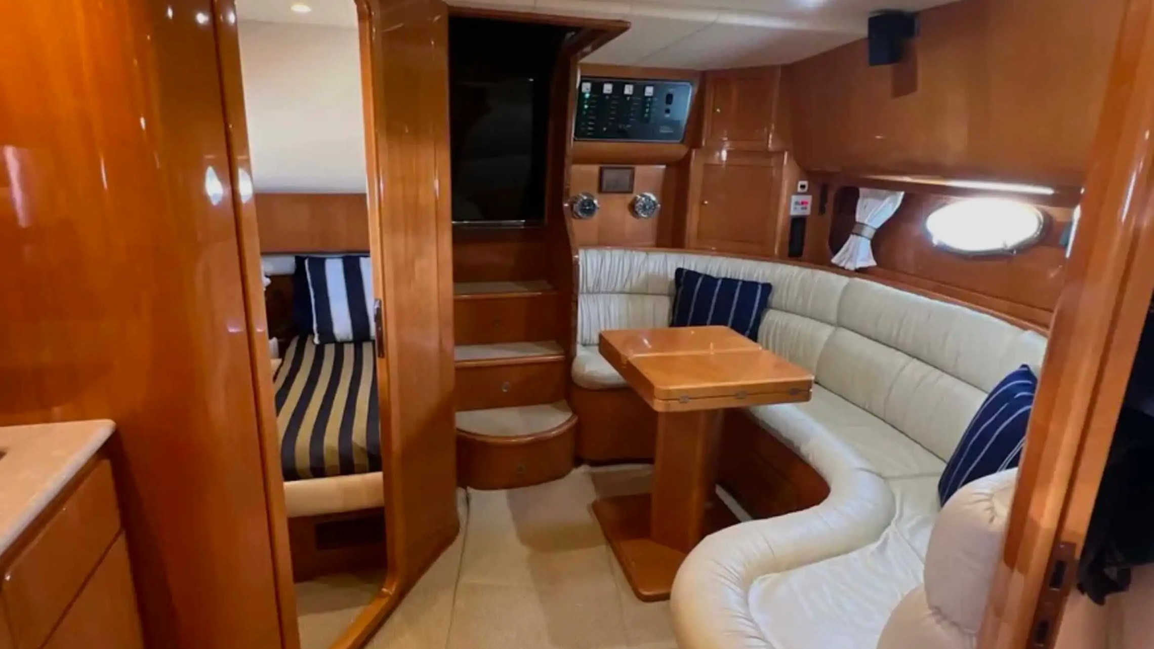 44' Uniesse Boat Rental with luxury cabin lounge, wraparound seating and polished wood interior in Naples, Florida.