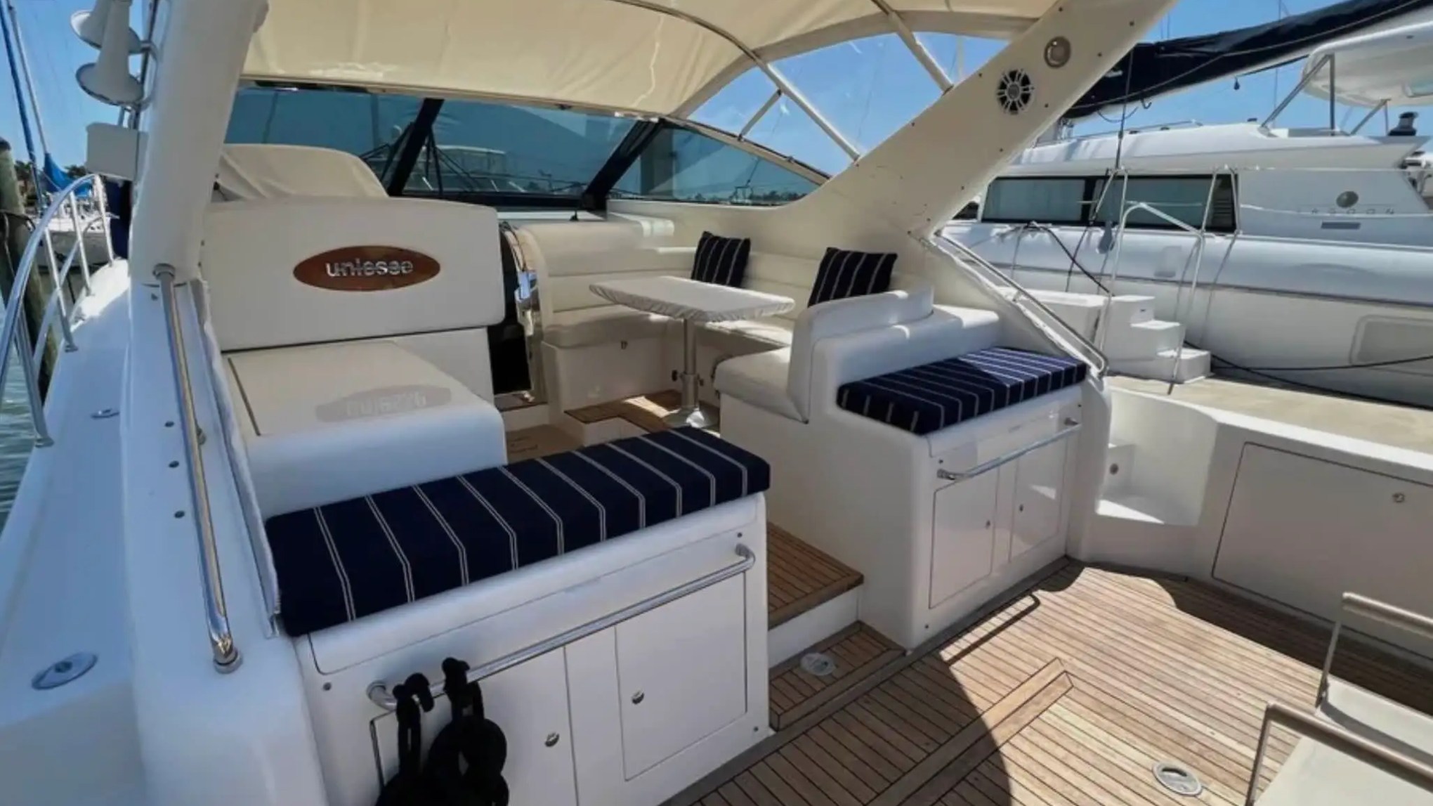 44' Uniesse Boat Rental with shaded cockpit lounge, dining table and teak deck in Naples, Florida.