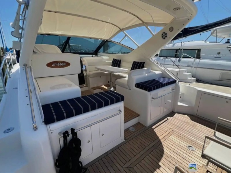 44' Uniesse Boat Rental with shaded cockpit lounge, dining table and teak deck in Naples, Florida.