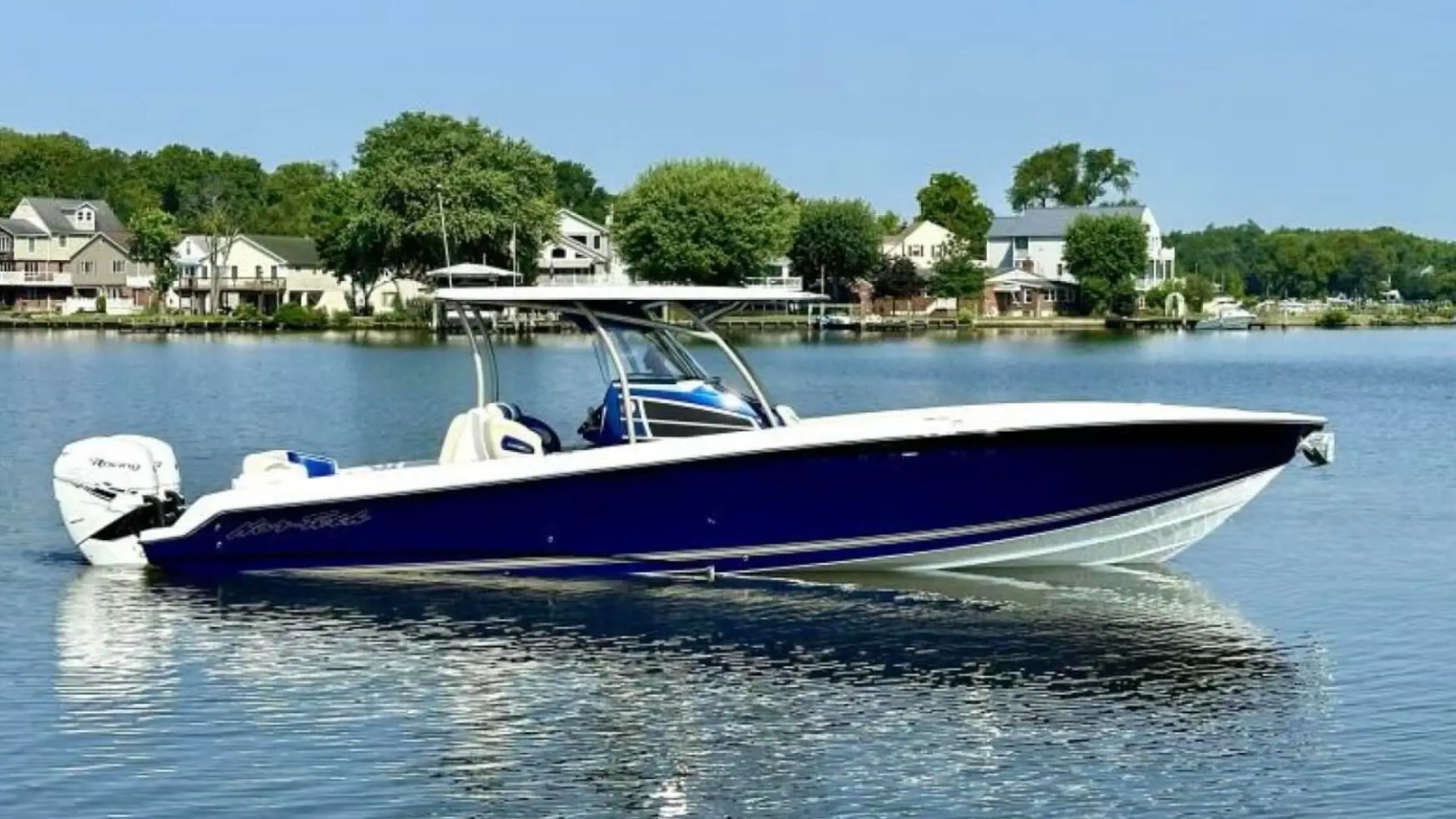 Nor-Tech Boat Rental with deep blue hull and hardtop cruising past waterfront homes on calm Florida waters.