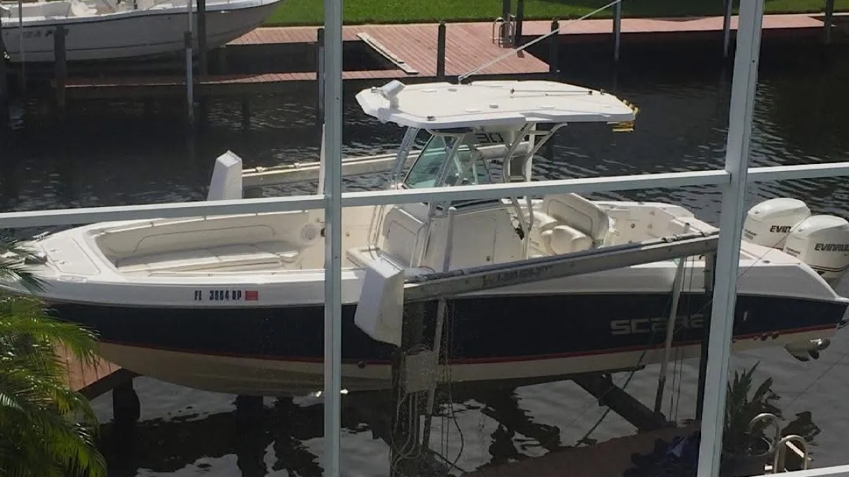 Scarab Boat Rental with twin outboards, hardtop and spacious bow seating docked on a South Florida canal.