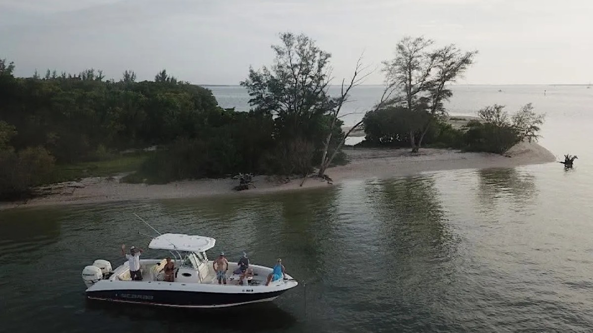 Scarab Boat Rental anchored beside a secluded South Florida island with guests enjoying calm coastal waters.