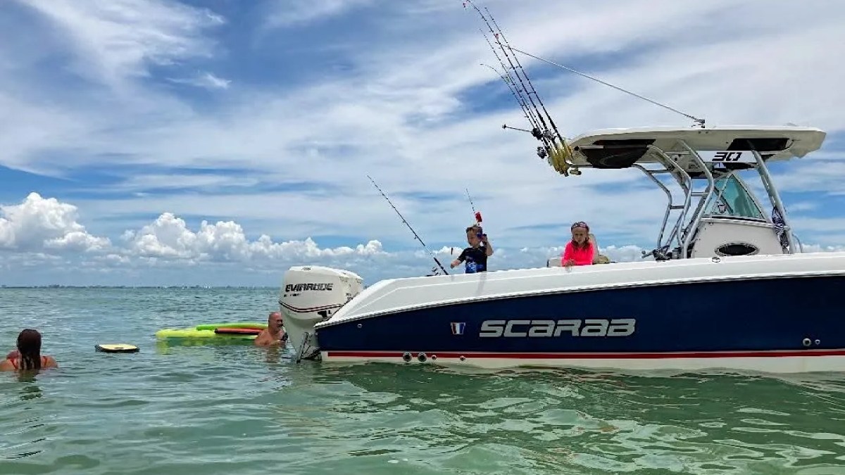Scarab Boat Rental anchored in shallow tropical water with guests swimming and relaxing beside the boat in South Florida.